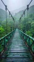 A suspension bridge stretches through a misty, lush forest, surrounded by dense green foliage, creating a serene and mystical atmosphere, evoking adventure and tranquility. photo