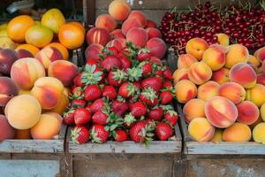 Fresh ripe peaches and strawberries displayed in cartons at a market, highlighting the colors and freshness of the fruits. photo