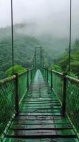 A suspension bridge stretches through a misty, lush forest, surrounded by dense green foliage, creating a serene and mystical atmosphere, evoking adventure and tranquility. photo