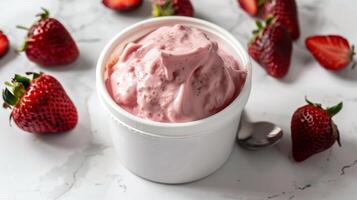 Delicious Strawberry Yogurt in Round Container with Fresh Strawberries on Marble Background photo