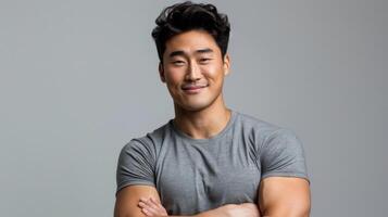Confident Fit Korean Man Standing with Arms Crossed in Gray TShirt, Studio Portrait for Professional Use photo