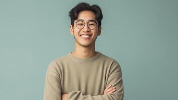 Smiling Young East Asian Man in Casual Outfit Standing with Arms Crossed Against a Calm Blue Background Perfect for Professional or Personal Use in Branding and Marketing photo