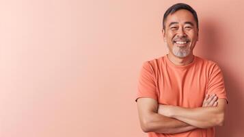 Smiling MiddleAged East Asian Man in Orange Shirt Against Peach Background for Welcoming and Friendly Design photo