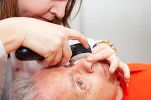 Dermatologist making a routine checkup on a senior male patient using a magnifying glass. photo