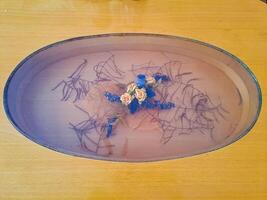 A wooden table with oval glass in the middle, which has a decoration of flowers photo