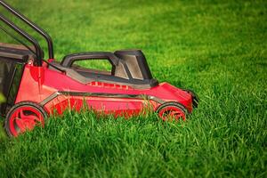 A red and black lawnmower on a background of green grass. photo