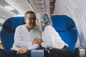 A mature couple enjoys a plane ride sitting near the window. They looked out into the sky. Immerse yourself in the scenery and excitement of the journey. To create precious memories together photo