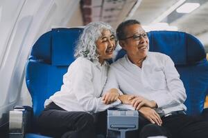 A mature couple enjoys a plane ride sitting near the window. They looked out into the sky. Immerse yourself in the scenery and excitement of the journey. To create precious memories together photo