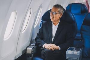 Attractive Asian male passenger of airplane sitting in comfortable seat while working laptop and tablet with mock up area using wireless connection. Travel in style, work with grace. photo