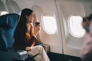 A female tourist is sitting inside a passenger plane, looking at the bird's eye view from the airplane window. photo