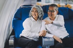 A mature couple enjoys a plane ride sitting near the window. They looked out into the sky. Immerse yourself in the scenery and excitement of the journey. To create precious memories together photo