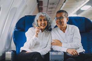 A mature couple enjoys a plane ride sitting near the window. They looked out into the sky. Immerse yourself in the scenery and excitement of the journey. To create precious memories together photo