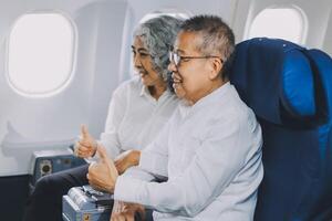 A mature couple enjoys a plane ride sitting near the window. They looked out into the sky. Immerse yourself in the scenery and excitement of the journey. To create precious memories together photo