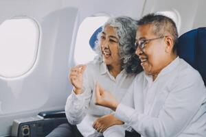 A mature couple enjoys a plane ride sitting near the window. They looked out into the sky. Immerse yourself in the scenery and excitement of the journey. To create precious memories together photo