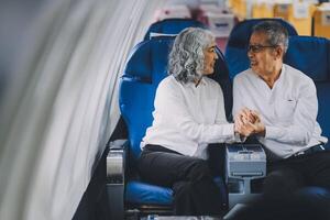 A mature couple enjoys a plane ride sitting near the window. They looked out into the sky. Immerse yourself in the scenery and excitement of the journey. To create precious memories together photo