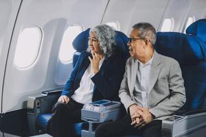 A mature couple enjoys a plane ride sitting near the window. They looked out into the sky. Immerse yourself in the scenery and excitement of the journey. To create precious memories together photo