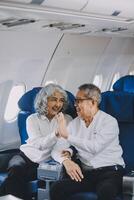 A mature couple enjoys a plane ride sitting near the window. They looked out into the sky. Immerse yourself in the scenery and excitement of the journey. To create precious memories together photo