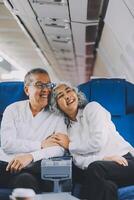 A mature couple enjoys a plane ride sitting near the window. They looked out into the sky. Immerse yourself in the scenery and excitement of the journey. To create precious memories together photo