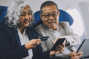 A mature couple enjoys a plane ride sitting near the window. They looked out into the sky. Immerse yourself in the scenery and excitement of the journey. To create precious memories together photo