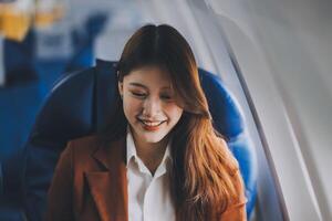 Young Asian executive excels in first class, multitasking with digital tablet, laptop and smartphone. Travel in style, work with grace. photo