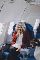 Mature with headache with nausea feeling sick while sitting in the airplane , Passengers near the window. photo