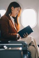 Young Asian executive excels in first class, multitasking with digital tablet, laptop and smartphone. Travel in style, work with grace. photo
