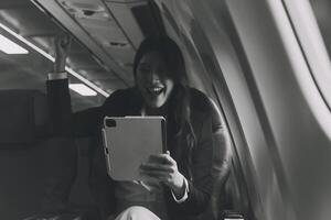 Young Asian executive excels in first class, multitasking with digital tablet, laptop and smartphone. Travel in style, work with grace. photo