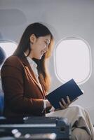 Young Asian executive excels in first class, multitasking with digital tablet, laptop and smartphone. Travel in style, work with grace. photo