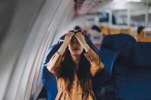 Joyful asian woman sits in the airplane and using tablet while go to travel photo