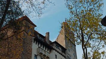 Beautiful fasade of Bran castle in Romania. Low angle view on the building and trees with little foliage. video
