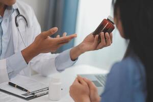 Doctor and patient sitting near each other at the wooden desk in clinic. Female physician's pointing to a records form. Medicine concept photo