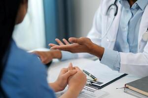 Doctor and patient sitting near each other at the wooden desk in clinic. Female physician's pointing to a records form. Medicine concept photo