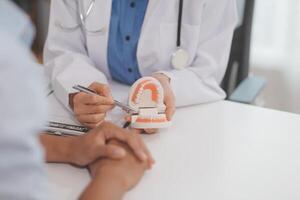 Dentist consultation - patient visit at the dental clinic office. Female dentist wearing dentures to explain teeth Recommend guidelines for orthodontics Dentist giving advice on patient's condition photo