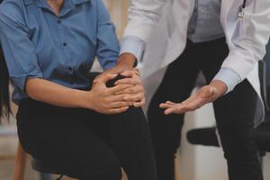 Professional orthopedist examining the little patient's leg in the clinic. Patient at the physiotherapy doing physical exercises with his therapist photo