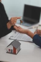 Estate agent giving house keys to client after signing agreement contract real estate with approved mortgage application form, concerning mortgage loan offer for and house insurance. photo