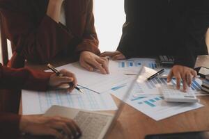 Group of confident business people point to graphs and charts to analyze market data, balance sheet, account, net profit to plan new sales strategies to increase production capacity. photo