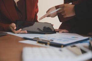 Group of confident business people point to graphs and charts to analyze market data, balance sheet, account, net profit to plan new sales strategies to increase production capacity. photo