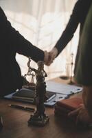 Lawyer shaking hands with a client making about documents, contracts, agreements, cooperation agreements with a female client at the lawyer's desk and a hammer at the table. photo