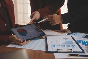 Group of confident business people point to graphs and charts to analyze market data, balance sheet, account, net profit to plan new sales strategies to increase production capacity. photo