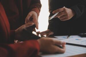Group of confident business people point to graphs and charts to analyze market data, balance sheet, account, net profit to plan new sales strategies to increase production capacity. photo
