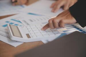 Group of confident business people point to graphs and charts to analyze market data, balance sheet, account, net profit to plan new sales strategies to increase production capacity. photo