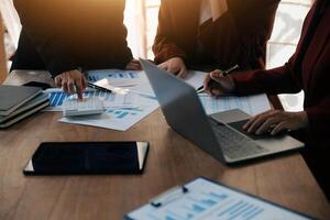 Group of confident business people point to graphs and charts to analyze market data, balance sheet, account, net profit to plan new sales strategies to increase production capacity. photo