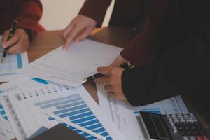 Group of confident business people point to graphs and charts to analyze market data, balance sheet, account, net profit to plan new sales strategies to increase production capacity. photo