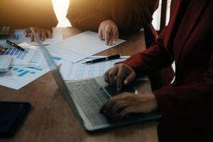Group of confident business people point to graphs and charts to analyze market data, balance sheet, account, net profit to plan new sales strategies to increase production capacity. photo