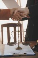 Lawyer shaking hands with a client making about documents, contracts, agreements, cooperation agreements with a female client at the lawyer's desk and a hammer at the table. photo