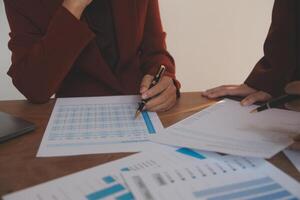Group of confident business people point to graphs and charts to analyze market data, balance sheet, account, net profit to plan new sales strategies to increase production capacity. photo