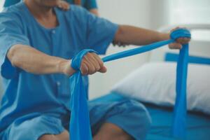 Close up hand patient doing stretching exercise with a flexible exercise band and a physical therapist hand to help in clinic room. photo