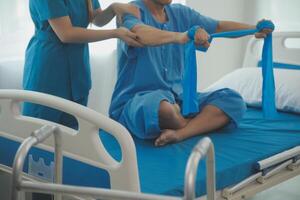 Close up hand patient doing stretching exercise with a flexible exercise band and a physical therapist hand to help in clinic room. photo