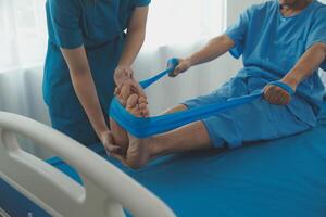 Professional orthopedist examining the little patient's leg in the clinic. Patient at the physiotherapy doing physical exercises with his therapist photo