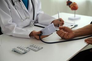 Doctor using sphygmomanometer with stethoscope checking blood pressure to a patient in the hospital. photo